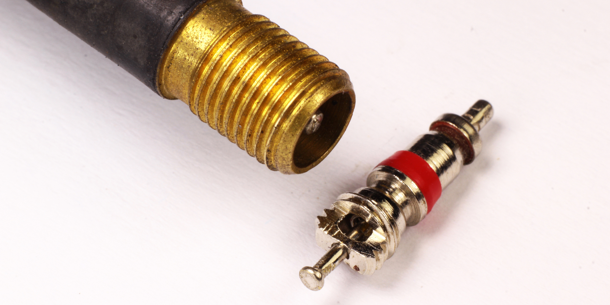 Detailaufnahme eines Ventil- und Adapterteils aus Metall, auf weißem Hintergrund.