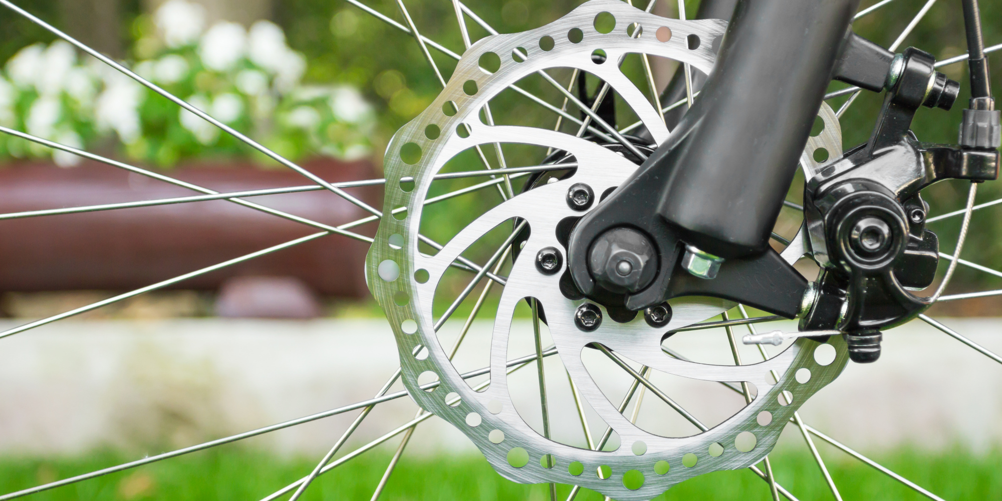 Nahaufnahme einer Fahrradbremsscheibe mit Speichen im Hintergrund.