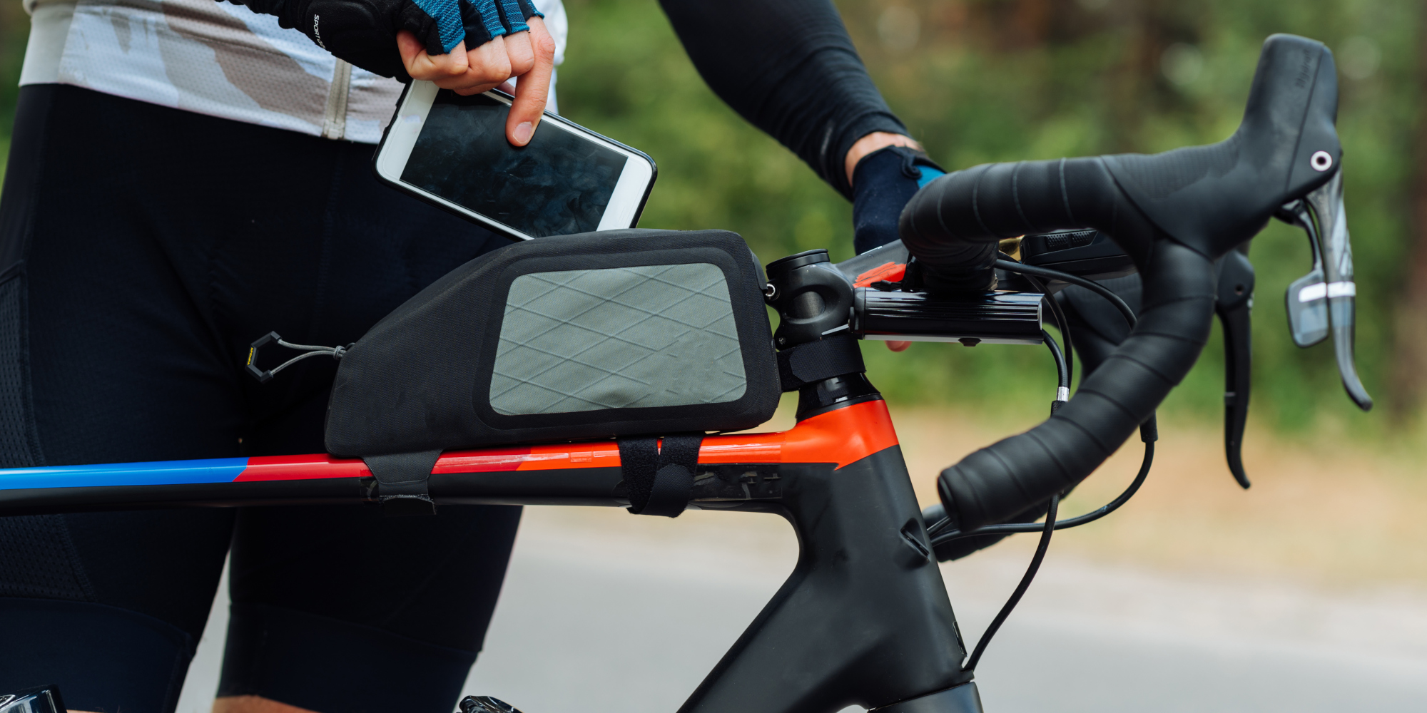 Frau holt Smartphone aus der Oberrohrtasche am Fahrrad