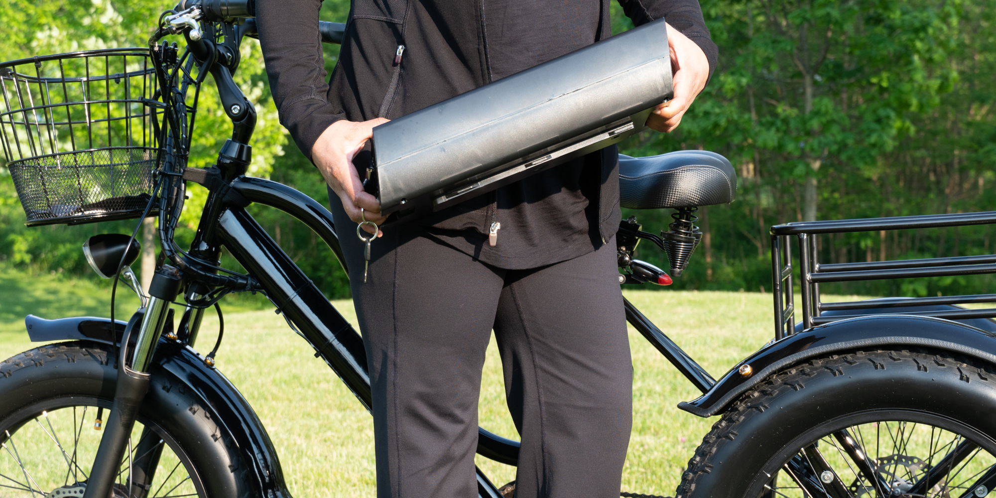 Eine Person in schwarzer Kleidung hält eine silberne Rolle neben einem E-Bike.