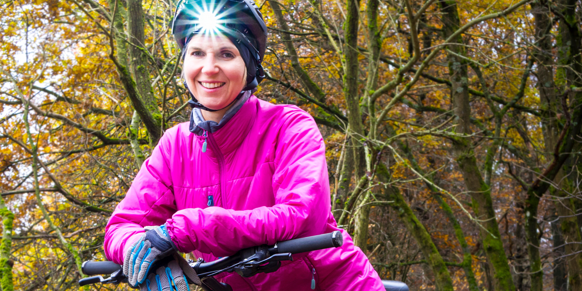 Beispielbild - LED-Fahrradhelm Frau auf dem Mountainbike mit Stirnlampe