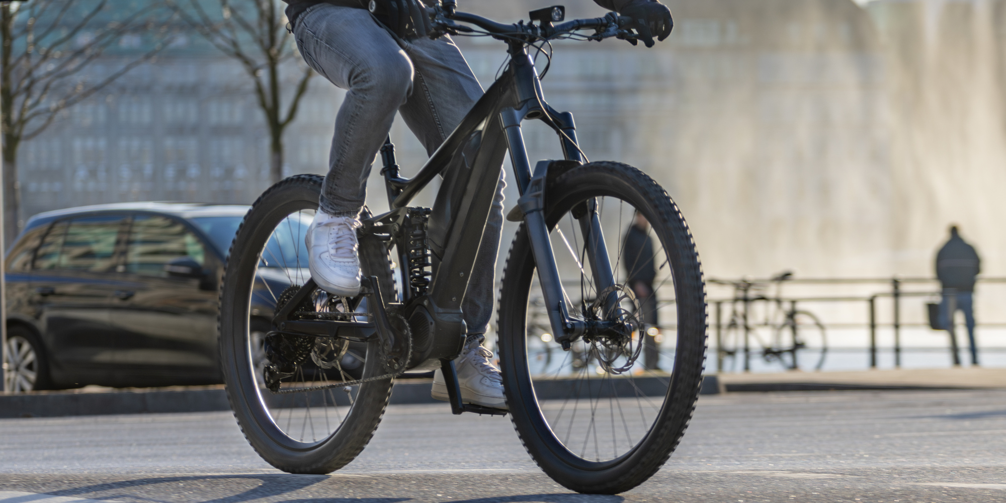 Radfahrer auf einem schwarzen E-Bike, vor einer fontänenartigen Kulisse.