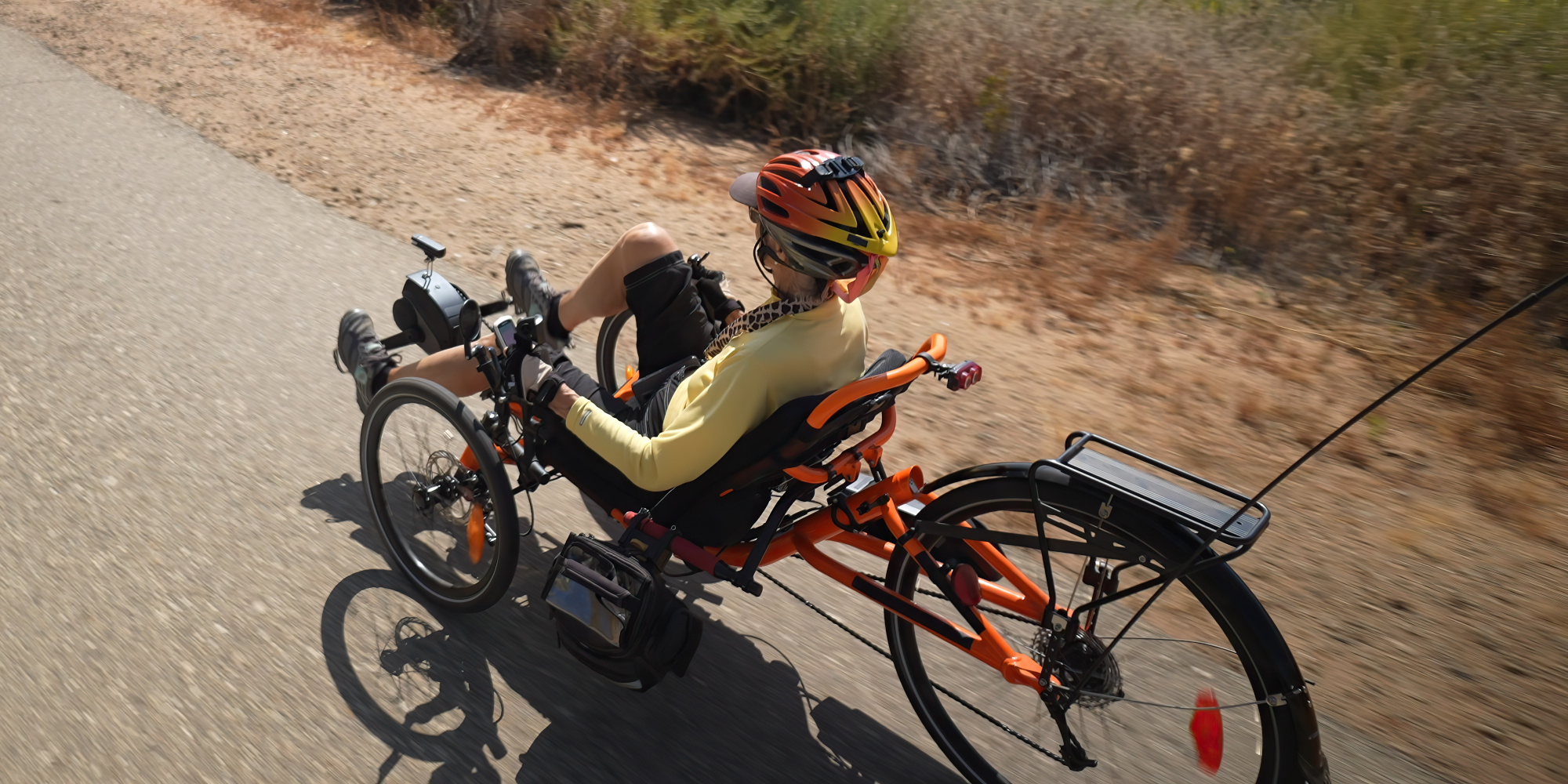 Person in einem Handbike auf einem asphaltierten Weg, helle Umgebung.