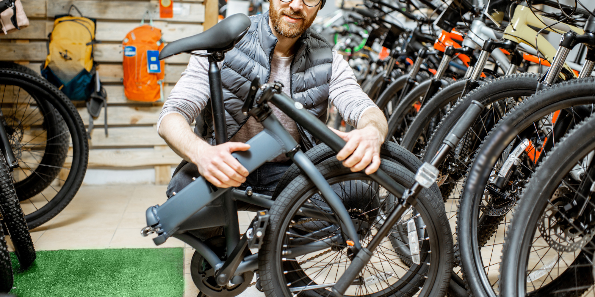 Welches Eovolt E-Bike Klapprad passt zu dir? Mann sitzt in einem Fahrradladen mit einem Faltrad in der Hand