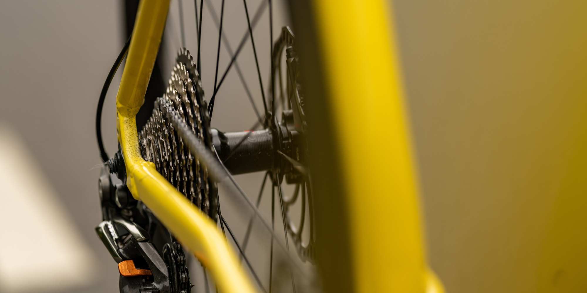 Nahaufnahme eines gelben Fahrradrahmens und des Hinterrads.