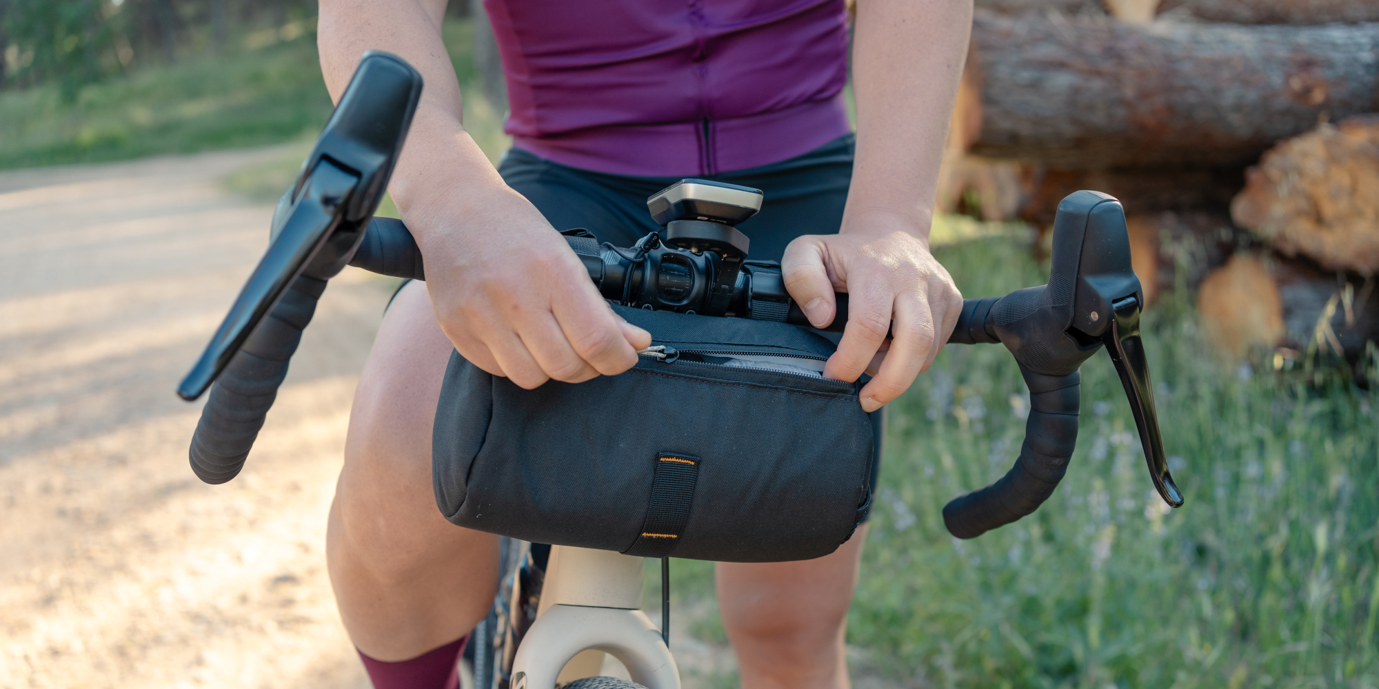 Eine Person greift nach einer Fahrradtasche am Lenker, um etwas herauszunehmen.