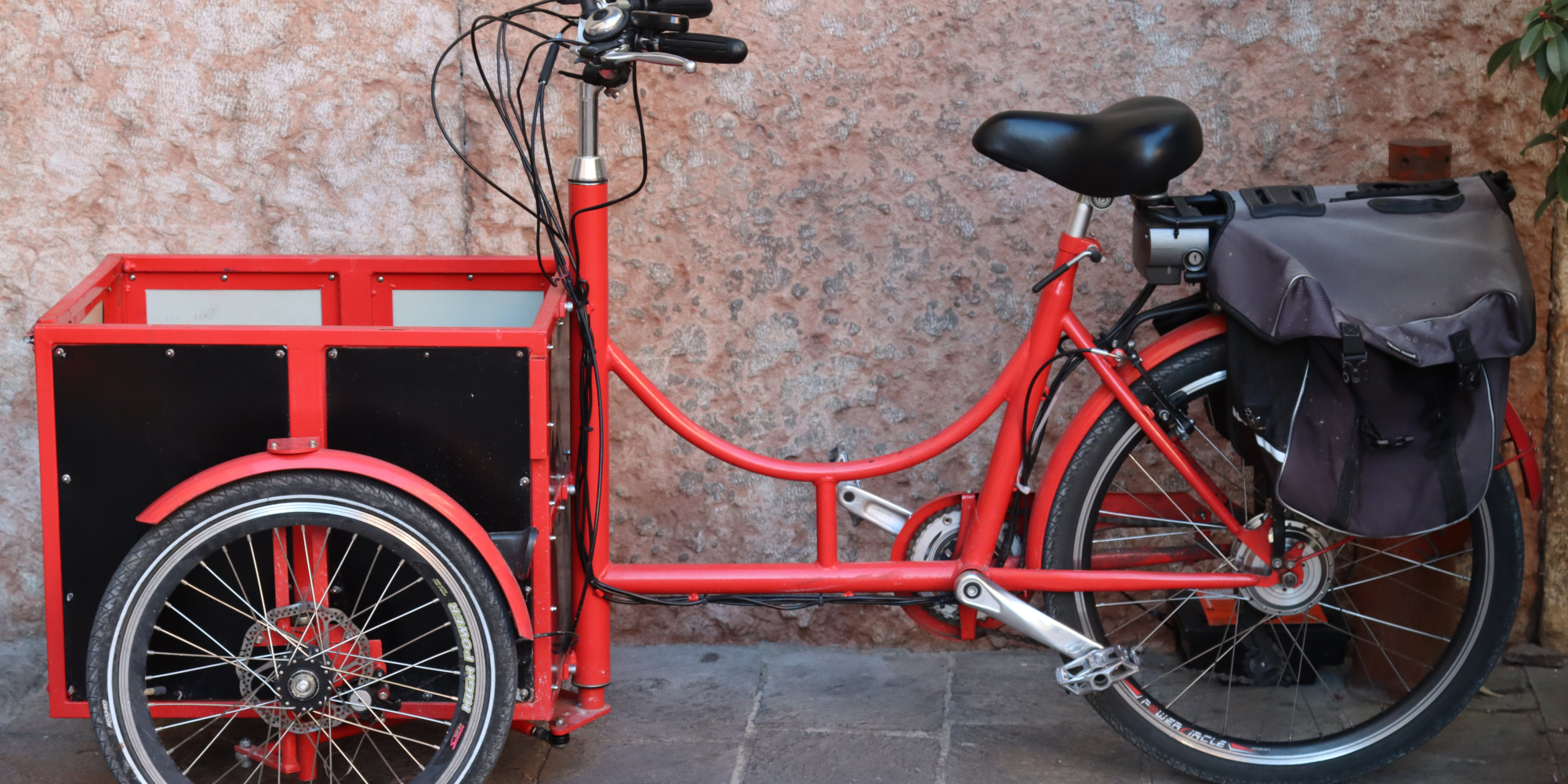 Rotes Lastenradlehnt an einer Wand