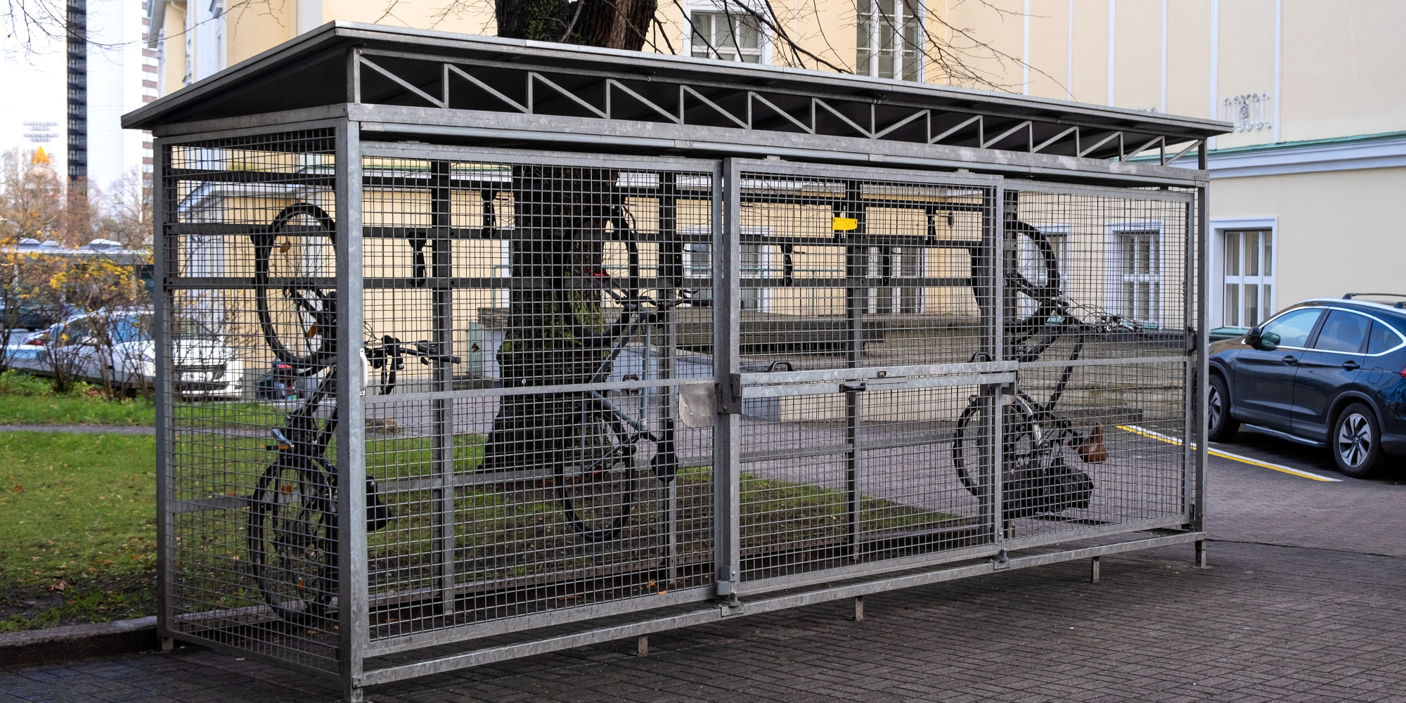 Fahrradabstellplatz mit einem Fenster aus Metall und mehreren eingeketteten Fahrrädern.