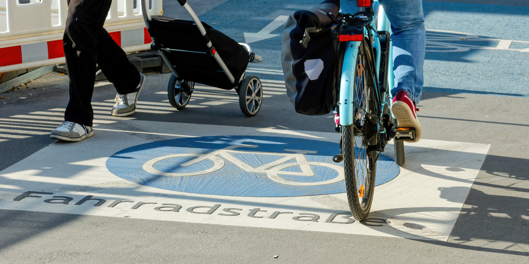 Radweg mit Fahrradfahrer und Fußgänger, blauer Boden mit Fahrradsymbol.