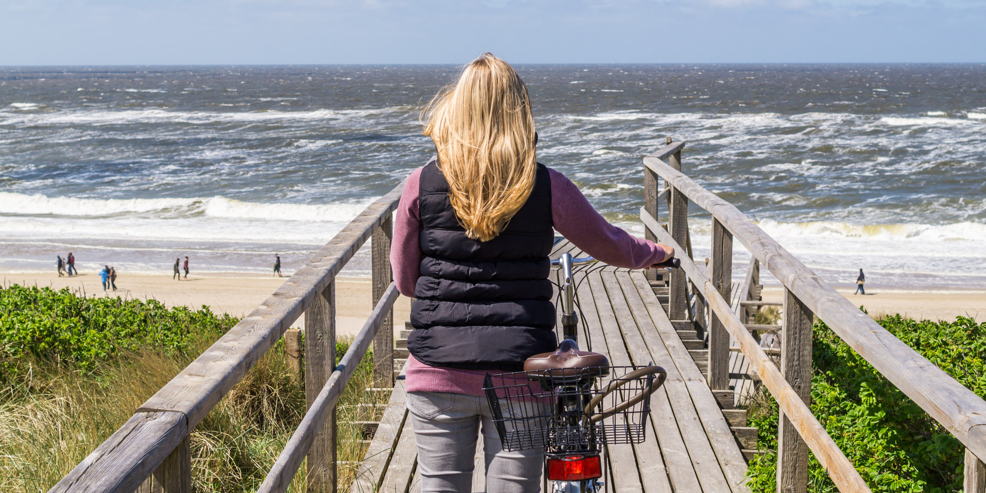 Frau mit Fahrrad auf dem Weg zum Meer auf Sylt