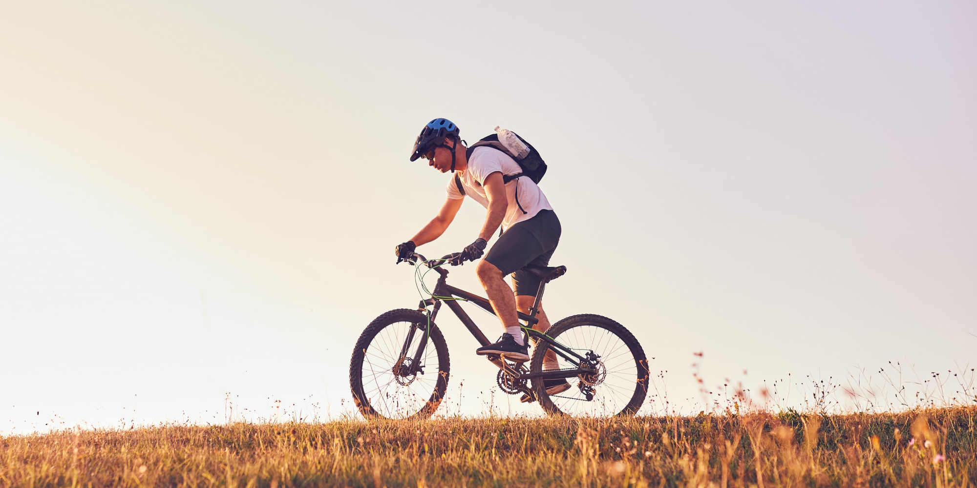 Focus Light E-MTB Vam² SL 9.9. Mann mit Helm, fährt mit E-MTB über Wiese