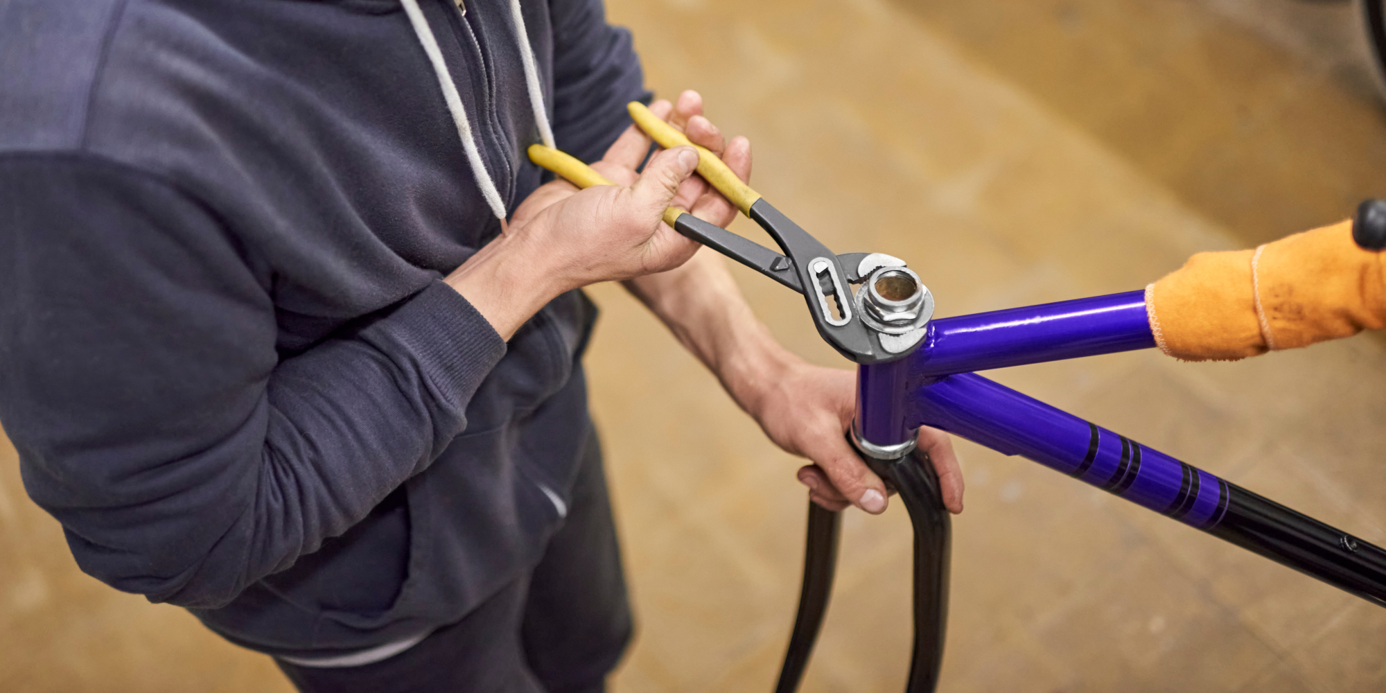 Ein Mechaniker repariert ein Fahrrad mit einer Zange in einer Werkstatt.
