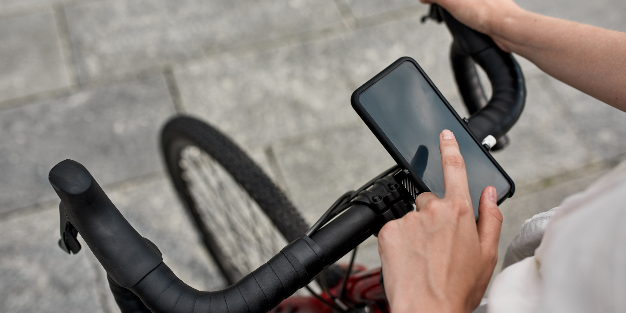 Eine Hand tippt auf das Smartphone, das am Fahrradlenker befestigt ist.