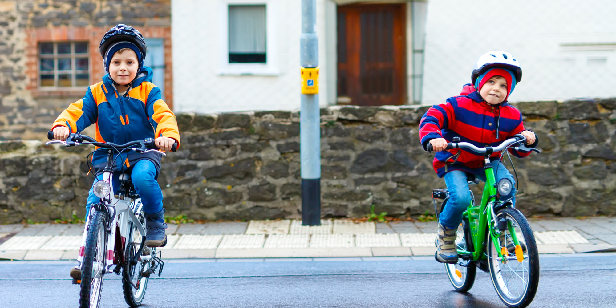 Zwei Kinder fahren fröhlich auf Fahrrädern bei leicht bewölktem Wetter.