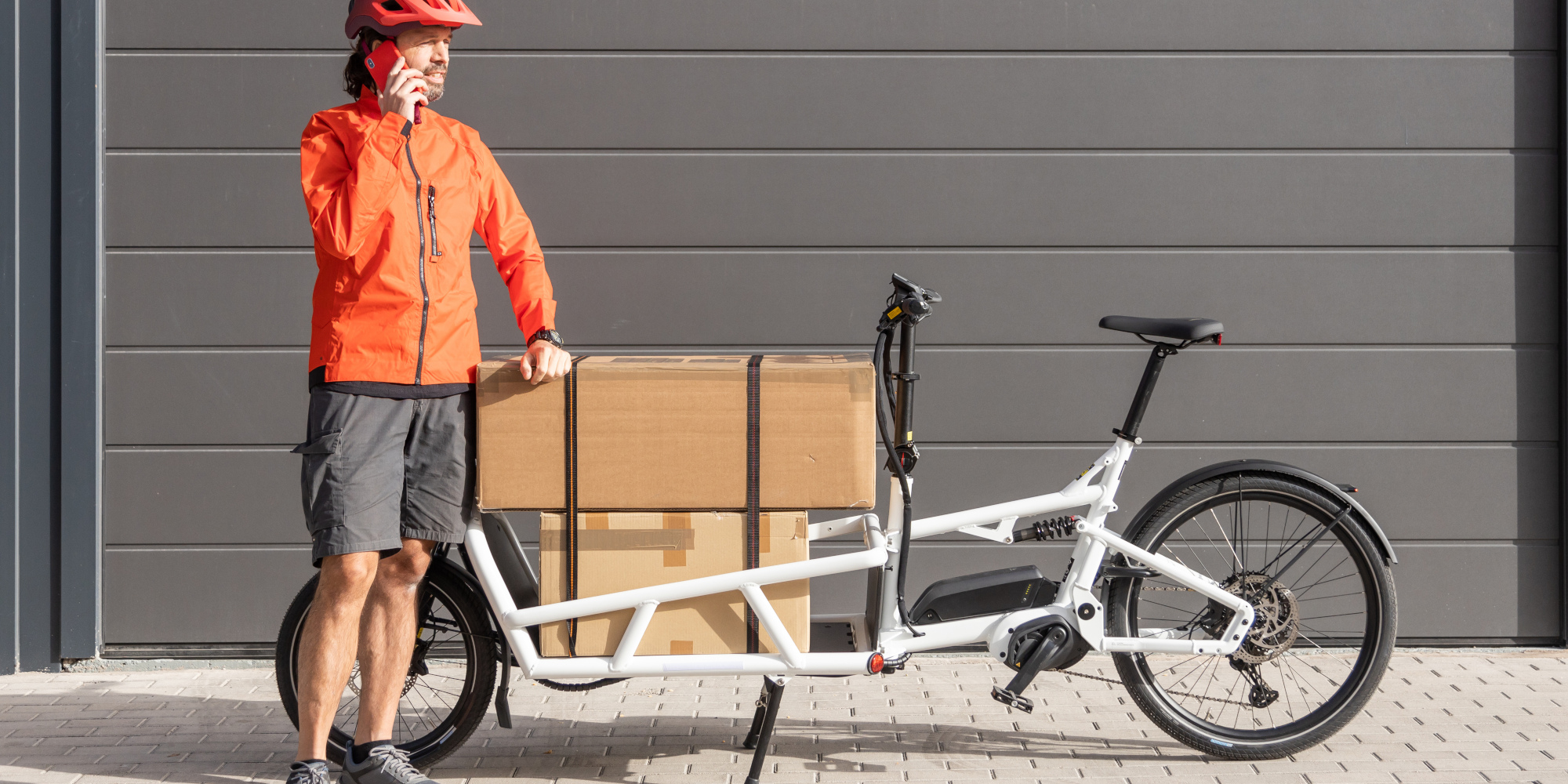 linexo präsentiert dir die Top 5 im Lastenrad-Test! Mann steht neben einem beladenem Lastenrad