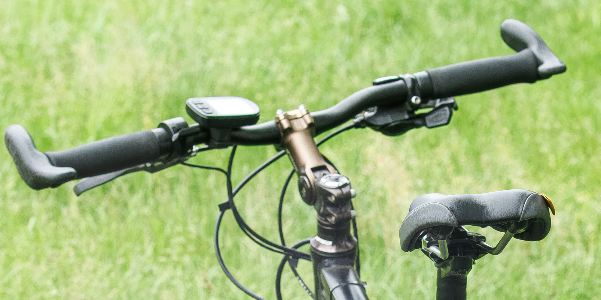 Fahrradlenker und Sattel auf einer Wiese, grüne Umgebung.