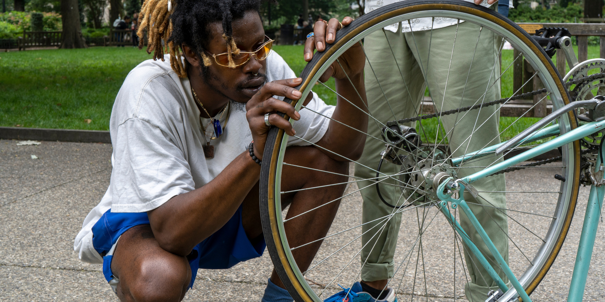 Ein Mann überprüft das Hinterrad eines Fahrrads in einem Park.
