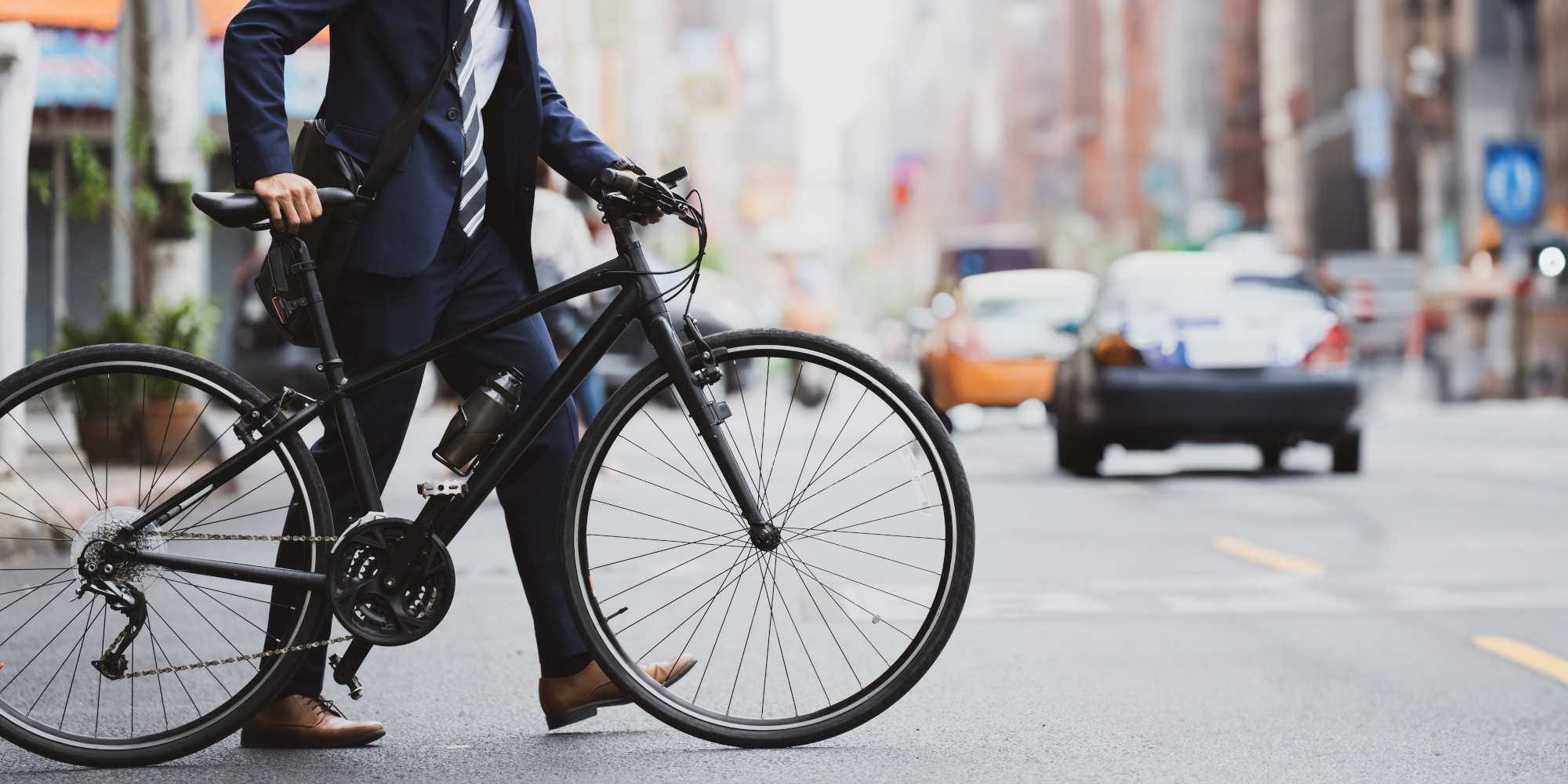 Die besten Urban Bikes Mann im Anzug schiebt sein Citybike durch die Stadt