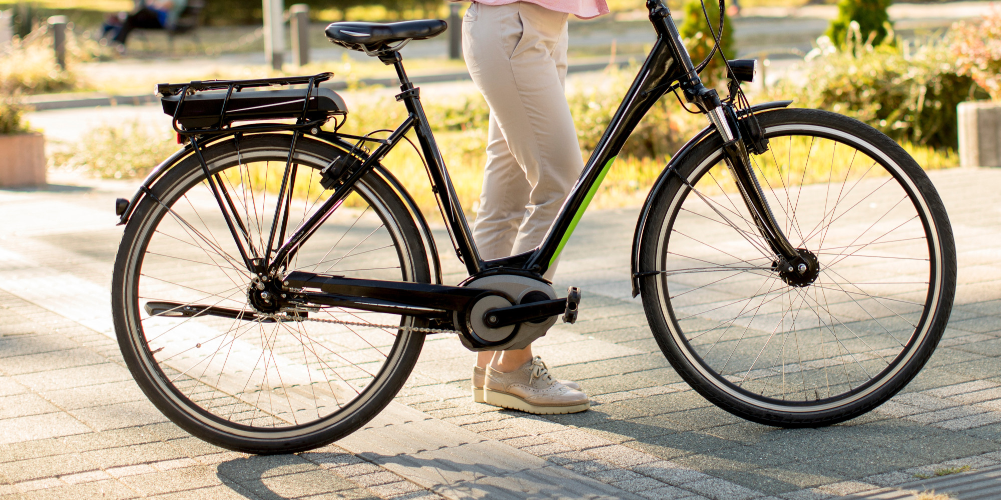 Schwarzes E-Bike steht auf einem Weg, eine Person steht daneben.