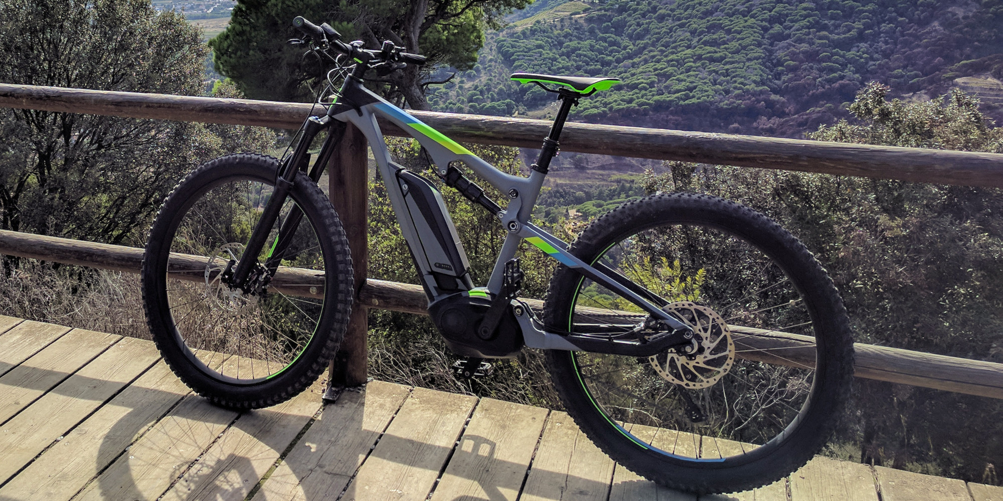 Ein Elektrofahrrad steht auf einem Holzdeck mit grünen und grauen Akzenten.