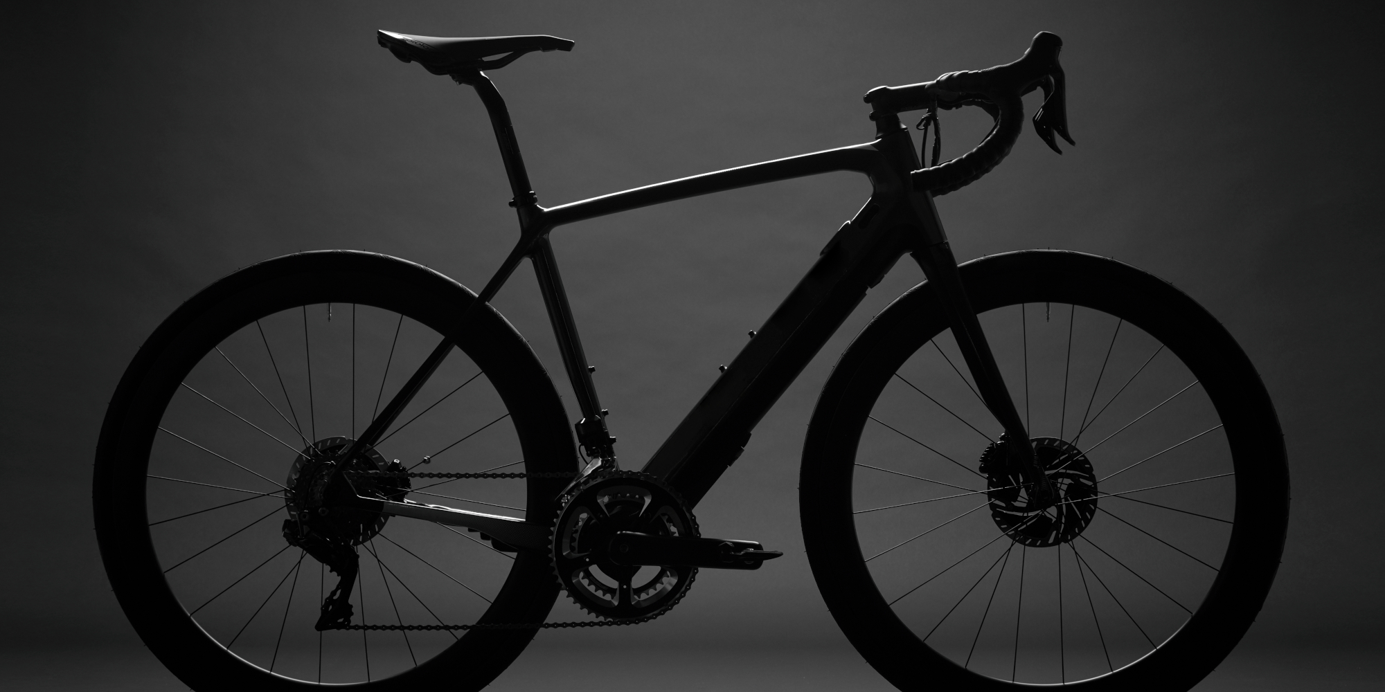 Schwarz silhouettiertes Fahrrad vor einem dunklen Hintergrund.