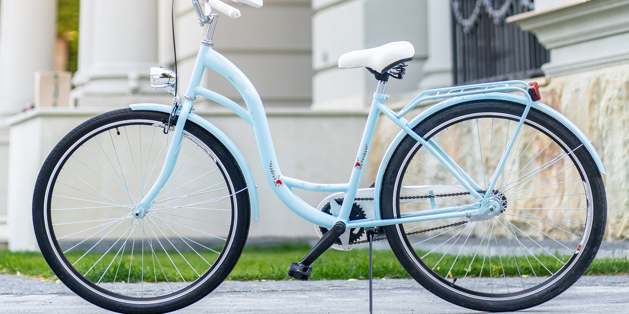 Helles, blaues Citybike steht auf einer Straße vor einem eleganten Gebäude.
