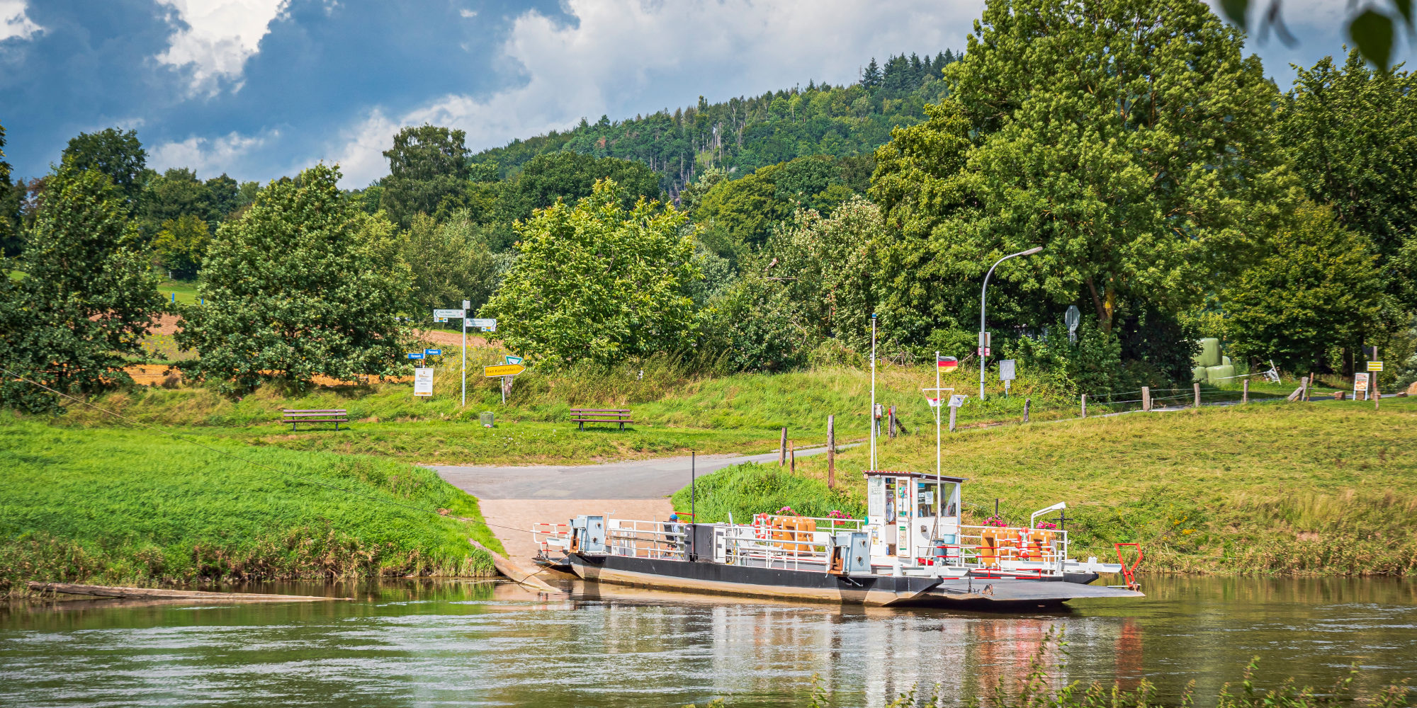 Die Fähre Lippoldsberg liegt am Ufer, umgeben von grünen Bäumen und Hügeln