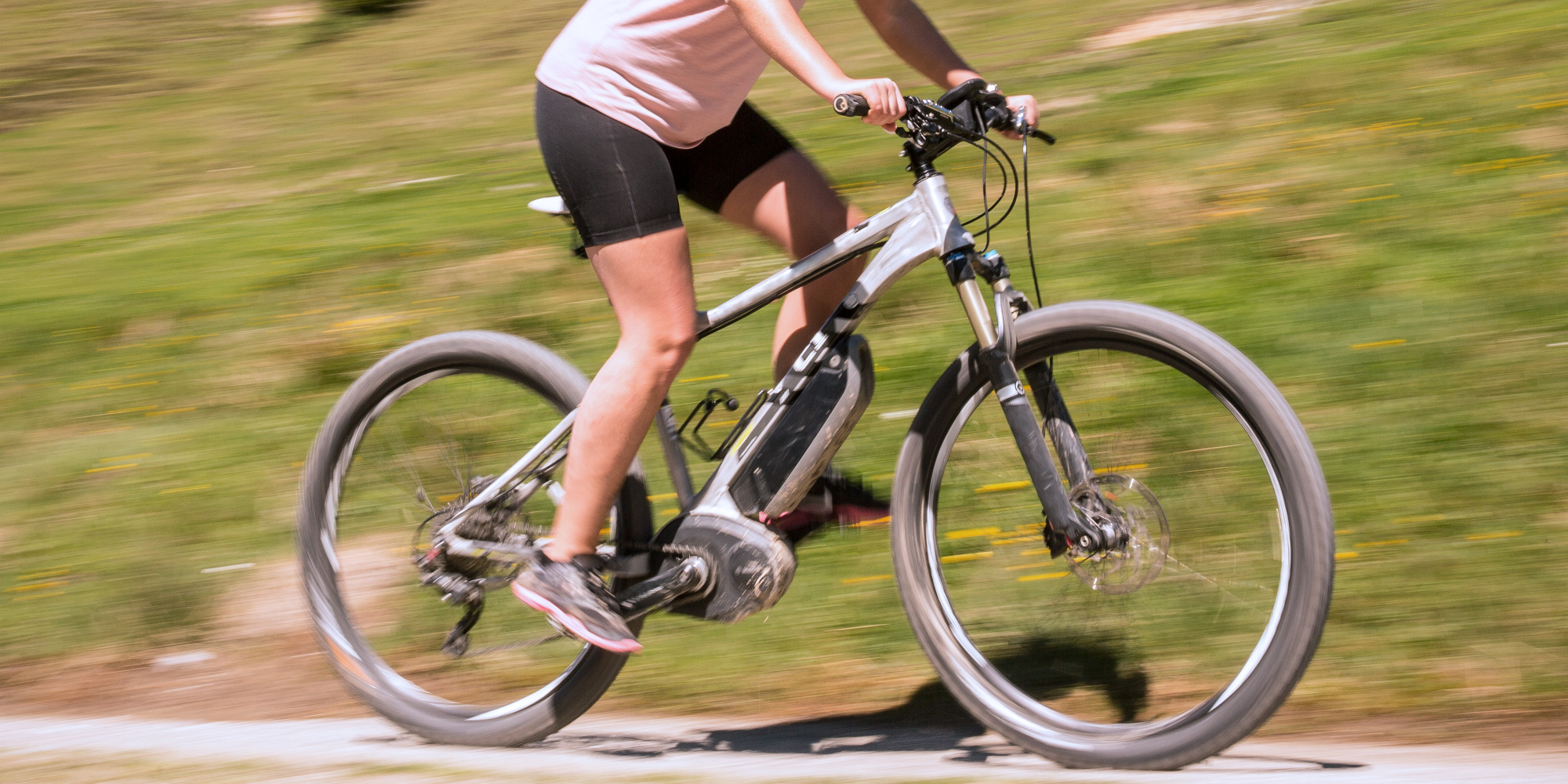 E-Mountainbike Frau fährt im Grünen mit einem E-Mountainbike