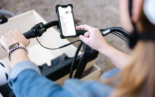Frau auf Lastenrad benutzt Fahrradpass in der linexo App