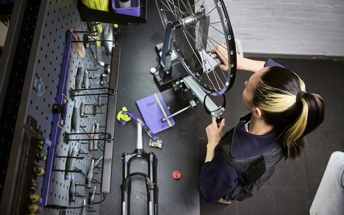 Eine Person arbeitet an einem Fahrradreifen in einer gut ausgestatteten Werkstatt.
