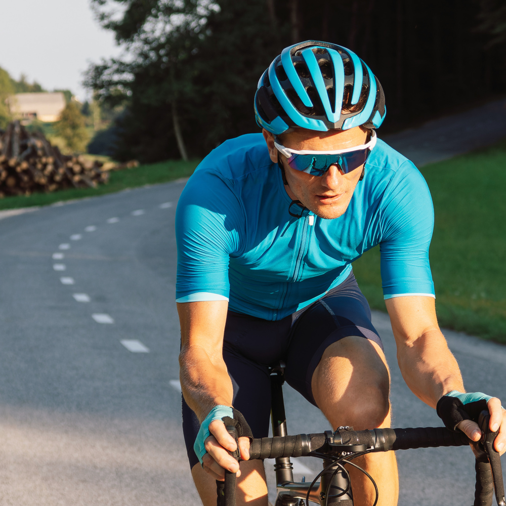 Entdecke Bianchi Rennräder und E-Bikes mit Tradition Man fährt auf einem Rennrad eine Straße hoch.