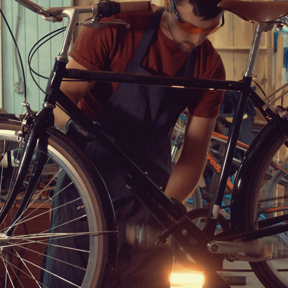 Mit unseren Tipps verwandelst du dein Bike zum Hingucker! Ein junger Mann schraubt an einem Fahrrad in einer Werkstatt.