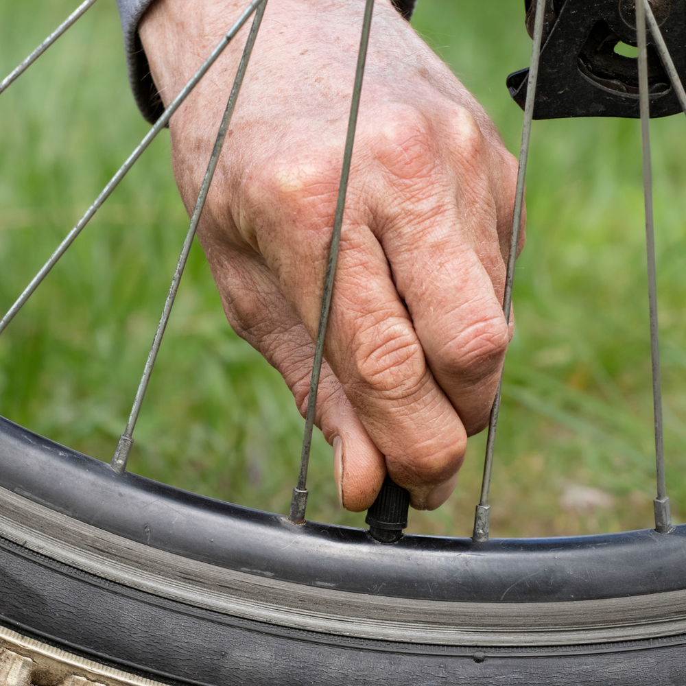 Entdecke die Fahrradventile von Schwalbe Nahaufnahme von einem Fahrradreifen mit einem Ventil, an dem eine Person anfässt.