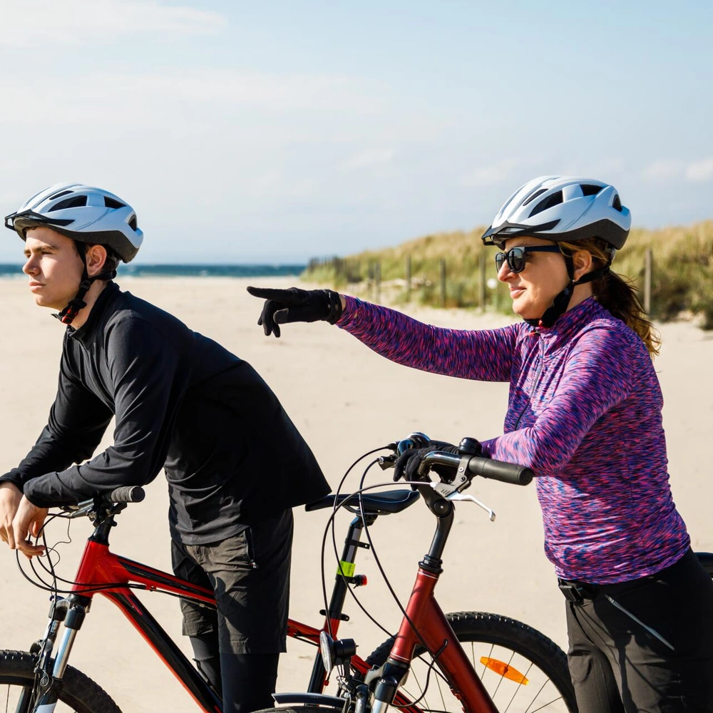 ATB-Bike Frau am Strand zeigt auf etwas, während ein Mann nachdenklich an seinem ATB-Bike lehnt
