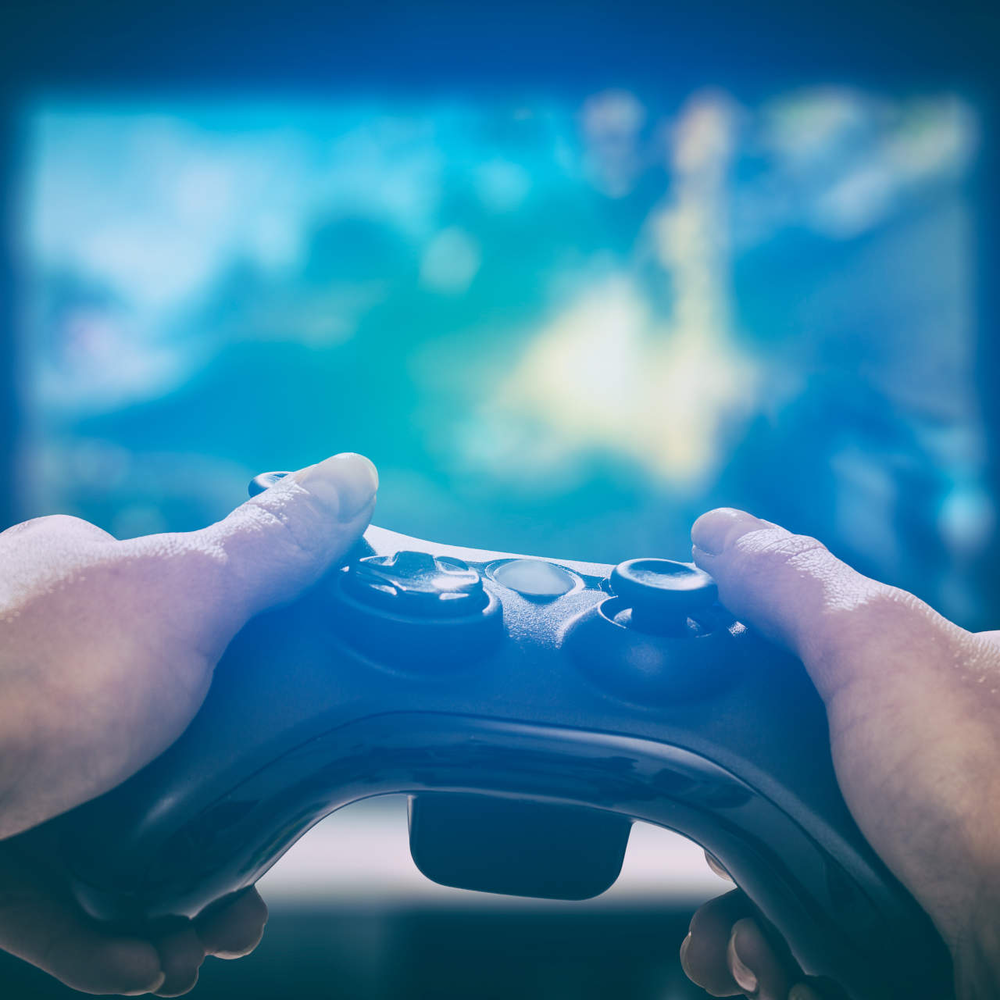 Bike Games - Die besten 5 Radspiele zum Zocken Gaming-Controller wird vor einen Bildschirm gehalten