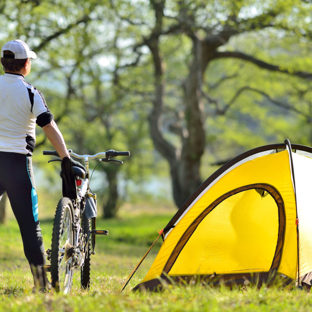 Bikepacking mit Zelt – darauf solltest du achten Ein Mann mit seinem Fahrrad und Zelt