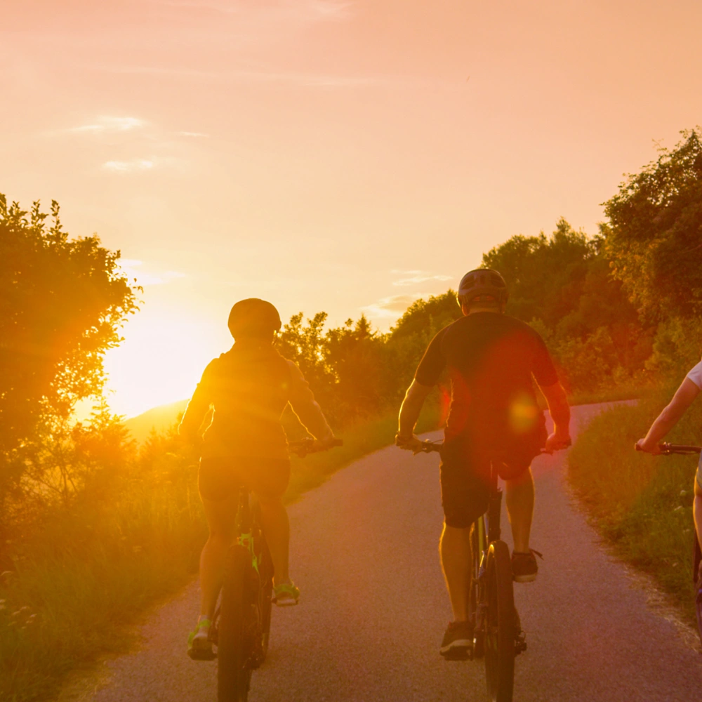 Drei Radfahrer genießen den Sonnenuntergang auf einem ruhigen Weg.