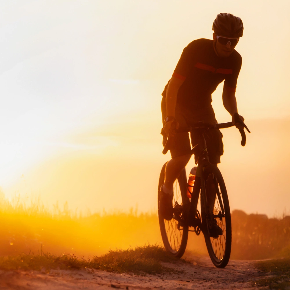 Radfahrer bei Sonnenuntergang auf einem staubigen Weg.