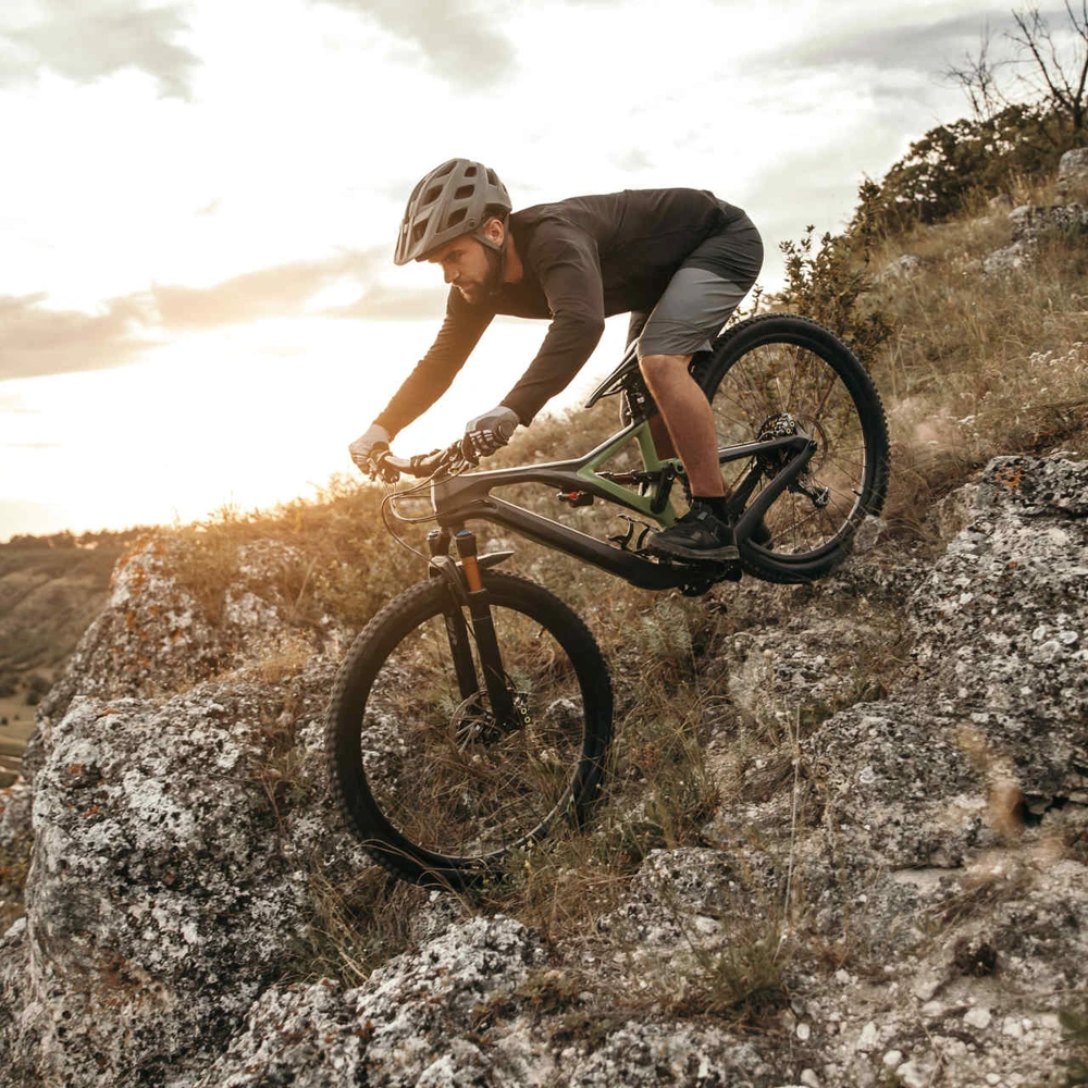 Die besten Bikeparks und Downhill Strecken in Deutschland. Mann fährt Mountainbike steilen Berg hinunter.