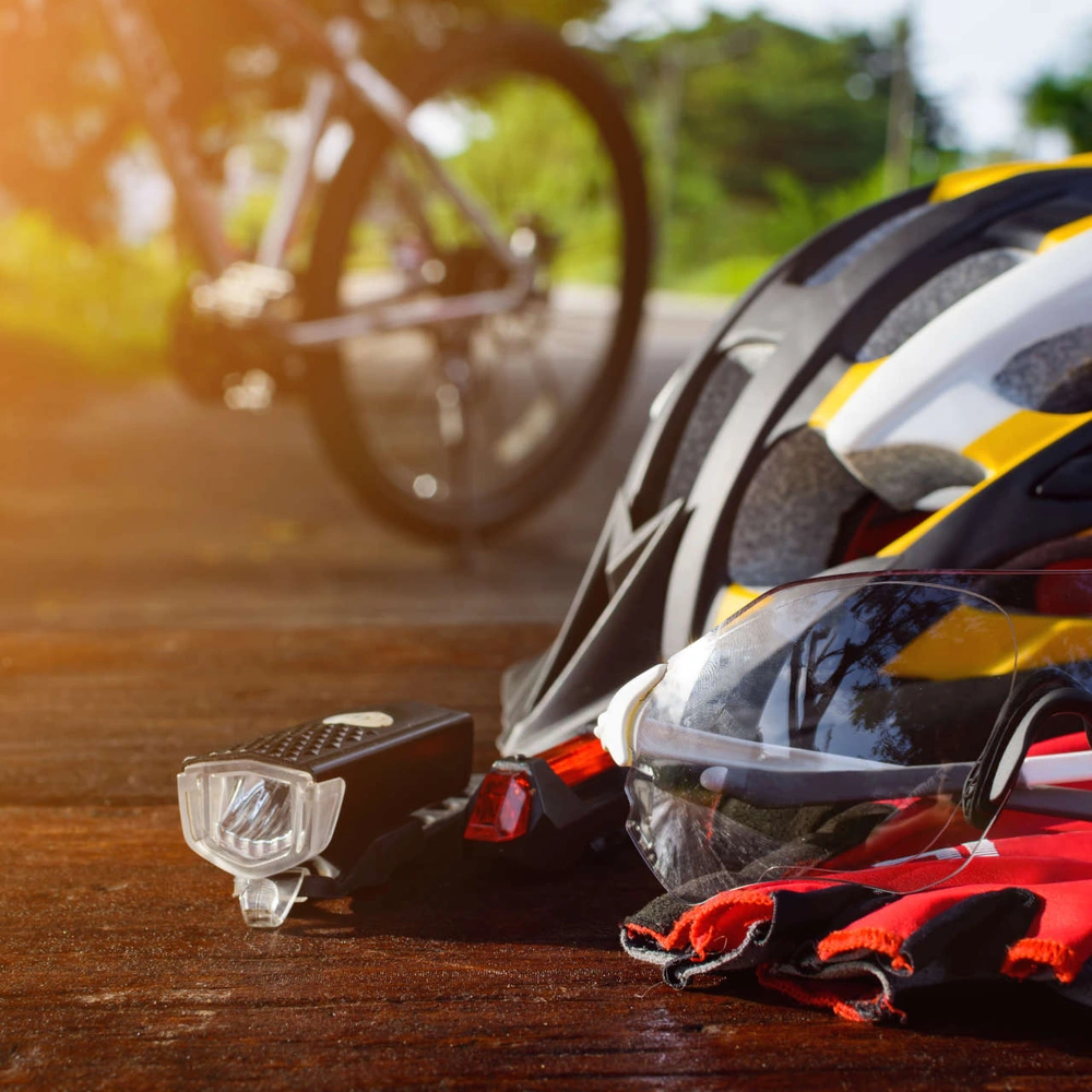 Ein Fahrradhelm, Sonnenbrille und Handschuhe liegen dem Boden, das Fahrrad ist im Hintergrund