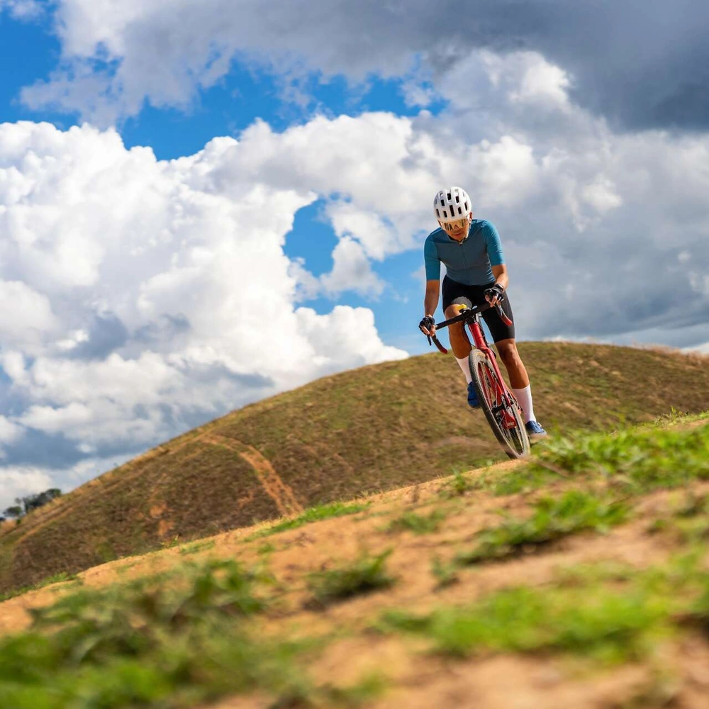 E-Crossbike Fahrer fährt Hügel runter bei bewölkten Himmel