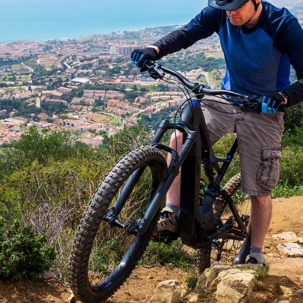 Alle Infos zum E-Mountainbike-Test: Die besten Modelle im Vergleich Mann fährt mit einem E-Mountainbike über einen Trail