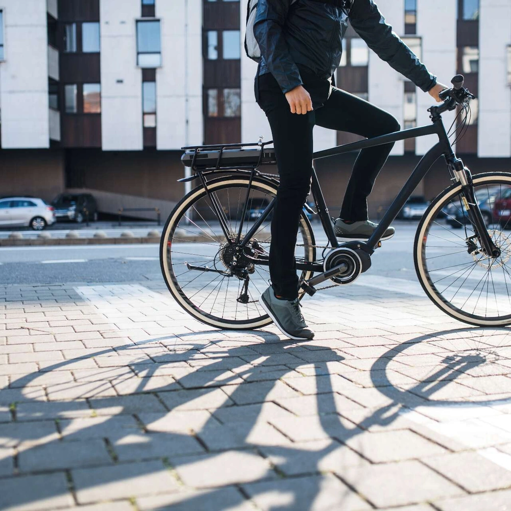 Person auf E-Trekkingbike fährt bei Sonne durch die Stadt