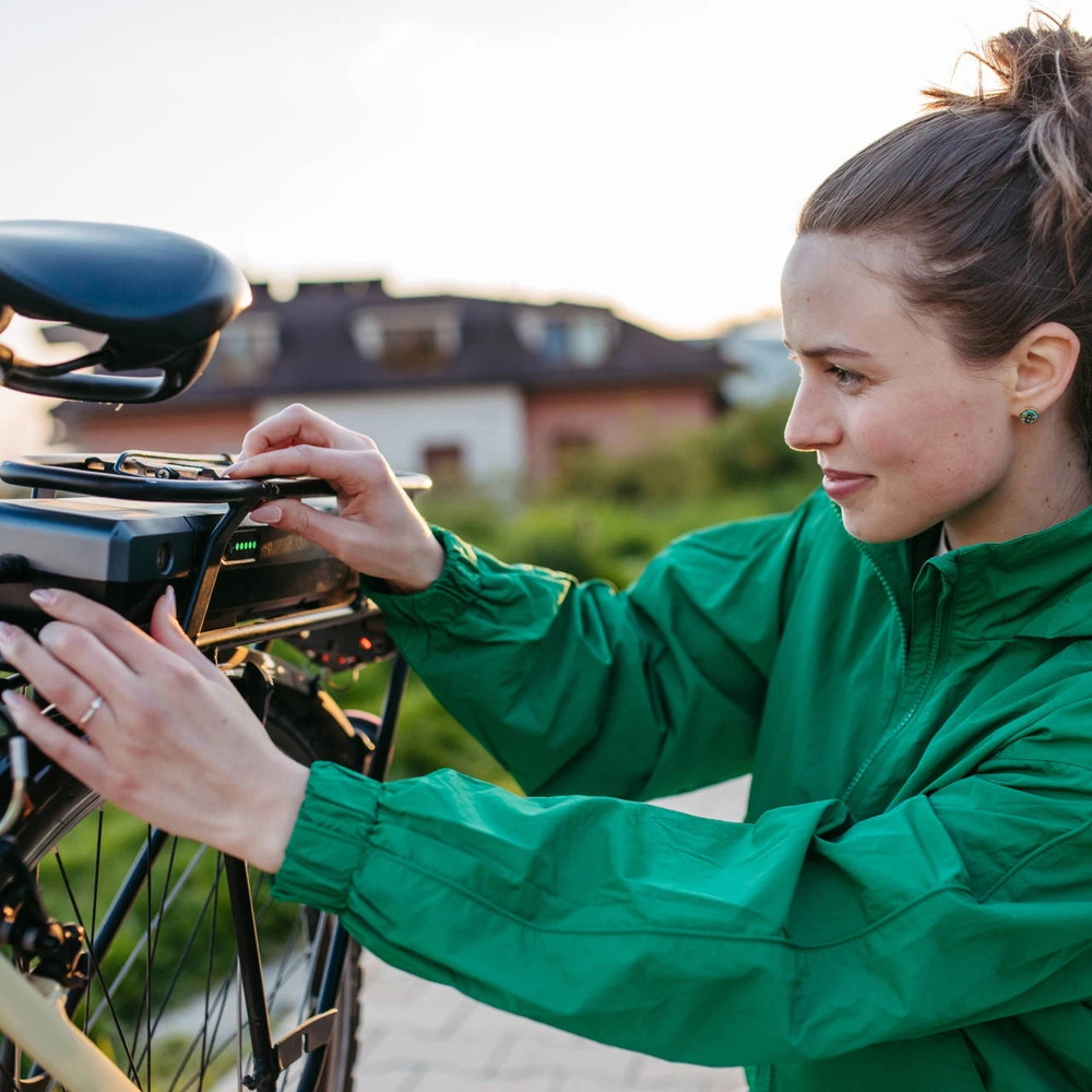Der Akku macht viel beim Gewicht eines E-Bikes aus Junge Frau schließt E-Bike Akku an