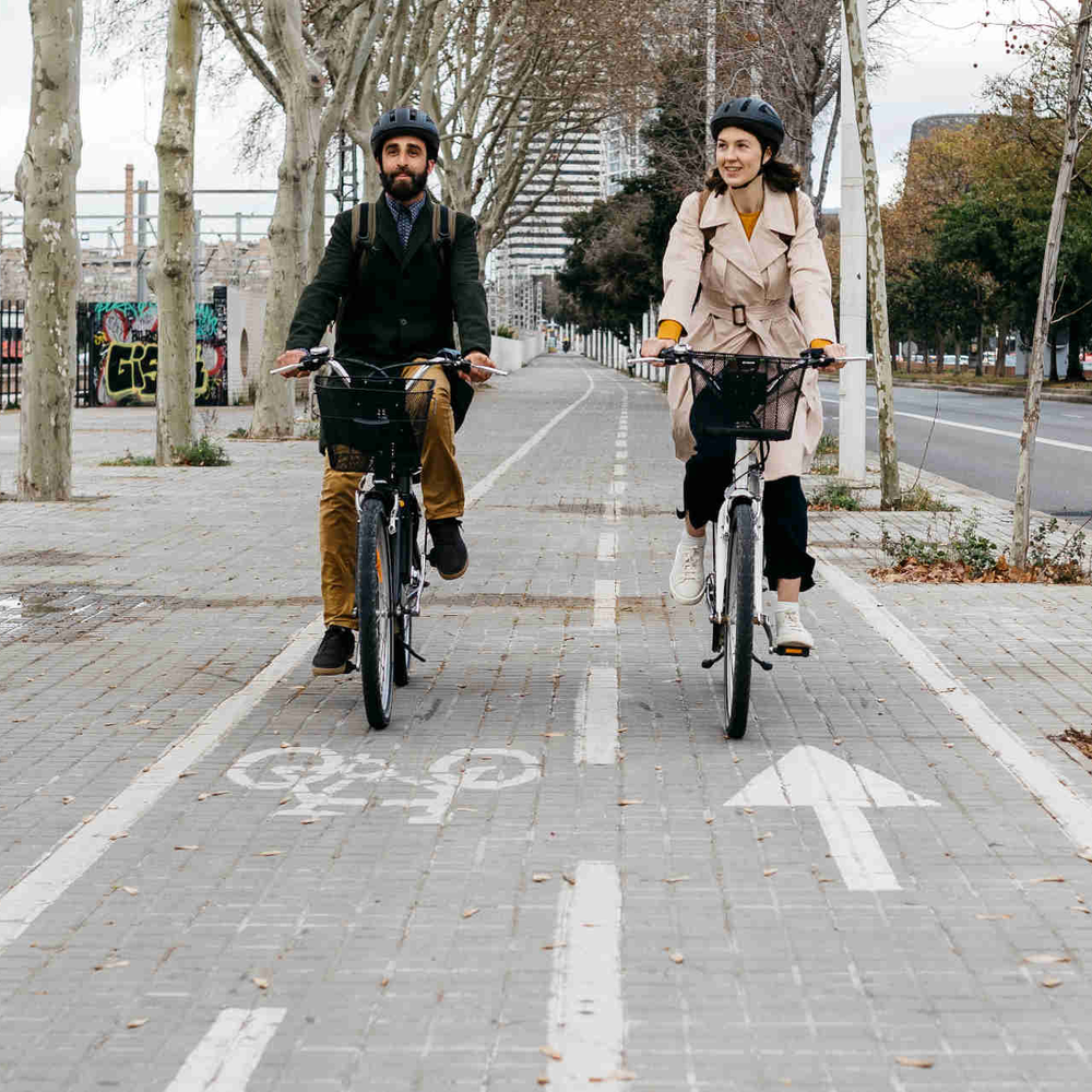 So bist du auf deinem E-Bike sicher unterwegs. Zwei Personen fahren nebeneinander auf Fahrrädern über einen Radweg.