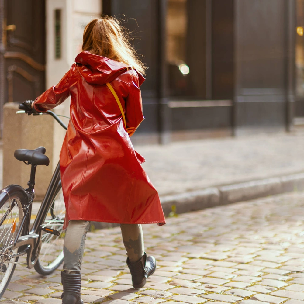 Trocken durch den Herbstregen mit einer Fahrrad Regenjacke Frau in Regenjacke schiebt Fahrrad