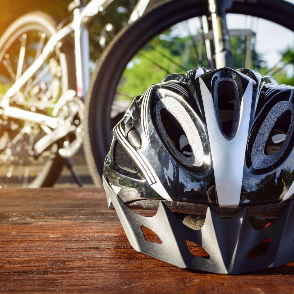 Fahrrad Zubehör - das sind die wichtigsten Bike-Produkte Ein Fahrradhelm liegt auf dem Tisch. Im Hintergrund befindet sich ein Mountainbike