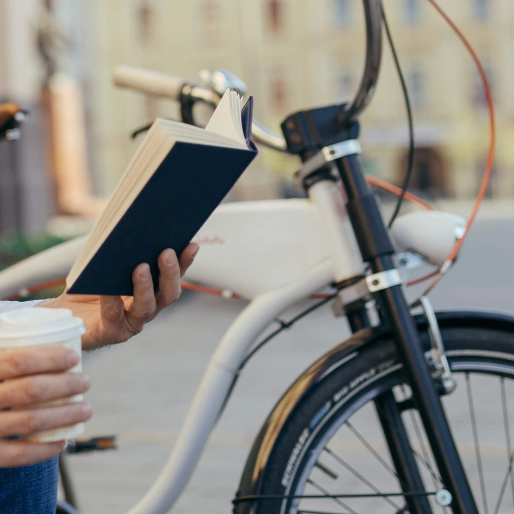 Die besten Fahrrad Buch Empfehlungen. Mann auf einer Bank liest ein Buch