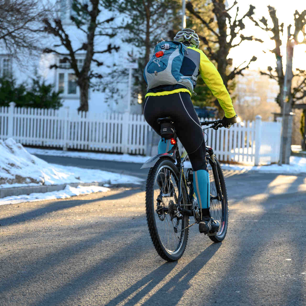 E-Bike fahren im Winter: Darauf musst du achten! Fahrradfahrer fährt im Winter auf Straße