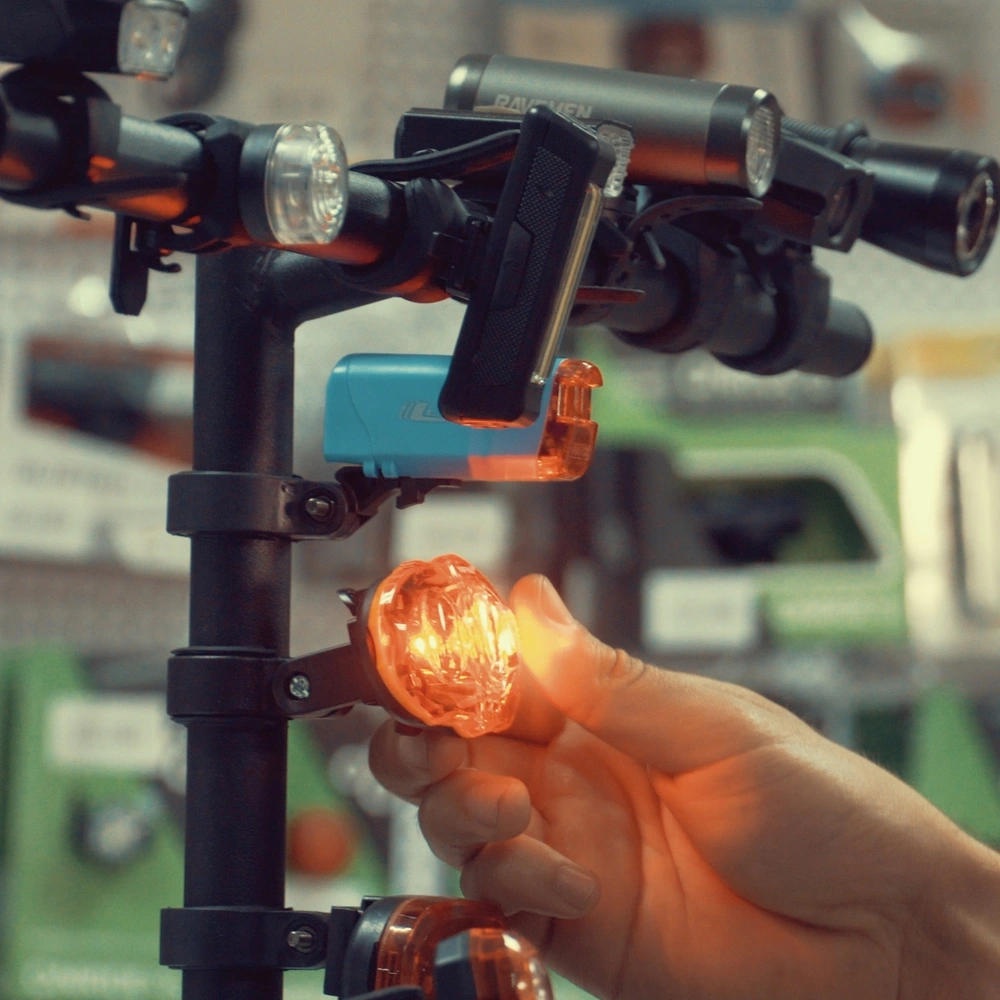 Eine Hand greift in einem Fahrradladen nach verschiedenen Fahrradlichtern auf einem Aufsteller